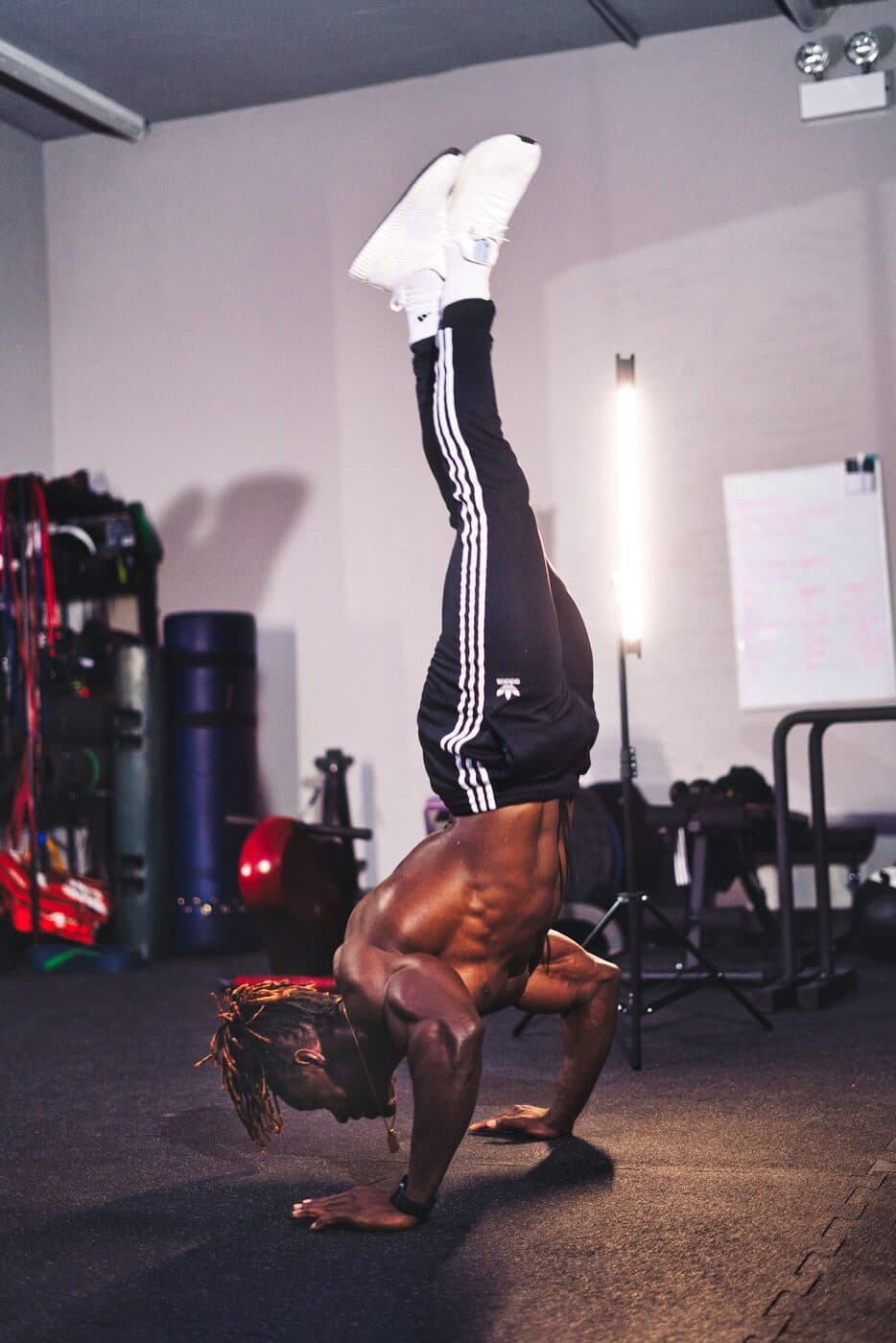 Alseny Sylla lowering into a bent-arm handstand push-up in a training room