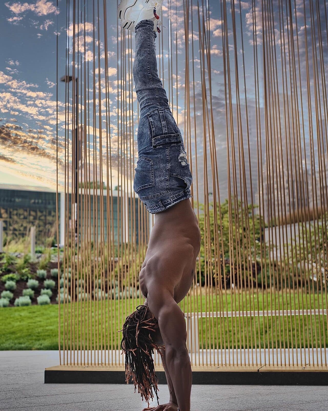 Alseny Sylla holding a clean, fully vertical freestanding handstand outdoors, legs together in a straight line